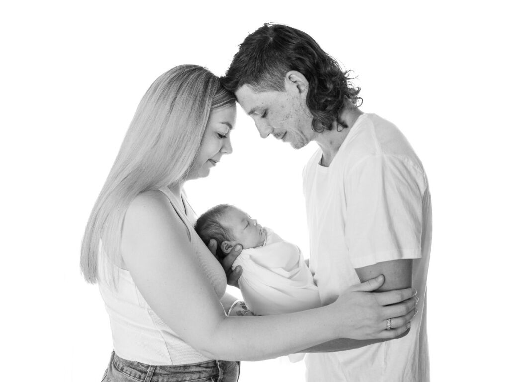 New parents lovingly cradling their newborn baby, captured in a timeless Pukekohe newborn photo.