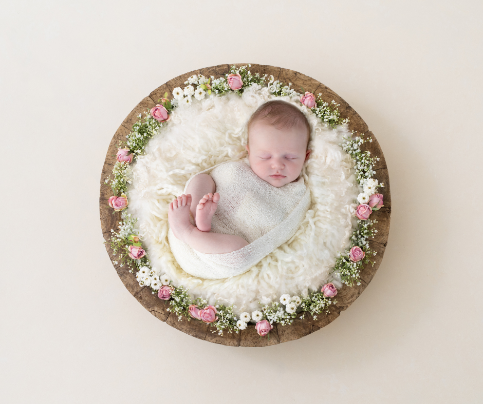 Newborn asleep on a fluffy blanket in a big wooden bowl.