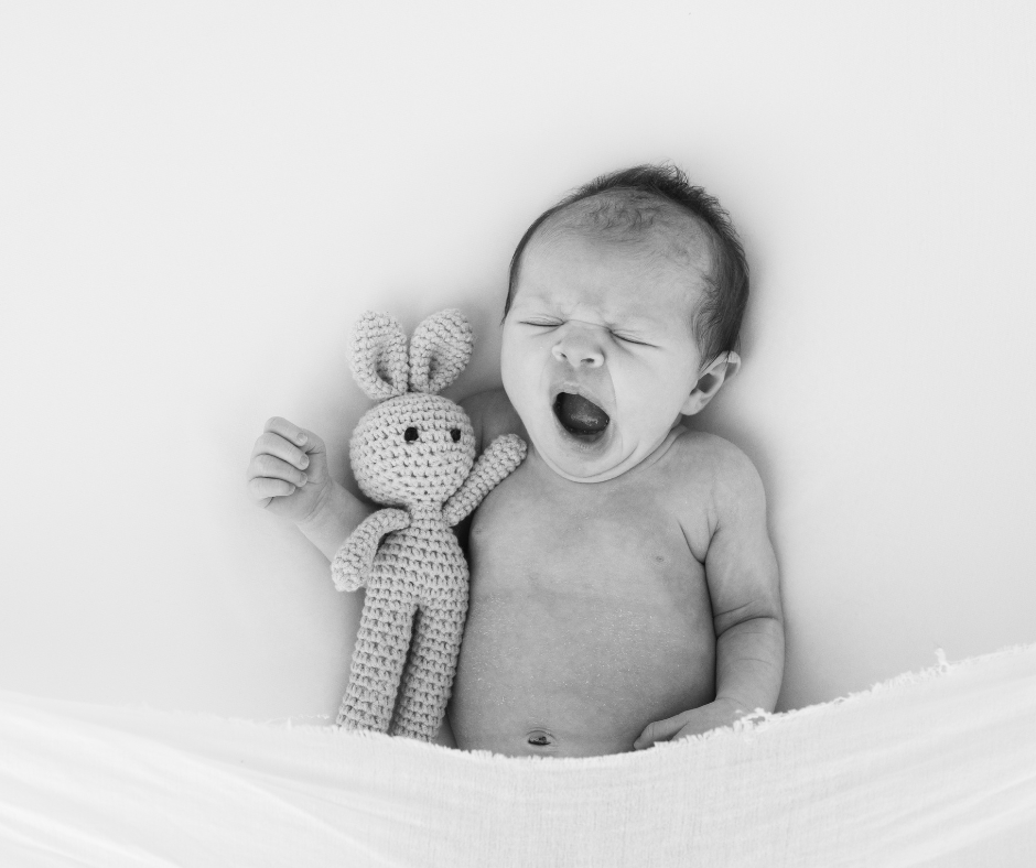 newborn baby yawning while tucked up in bed.