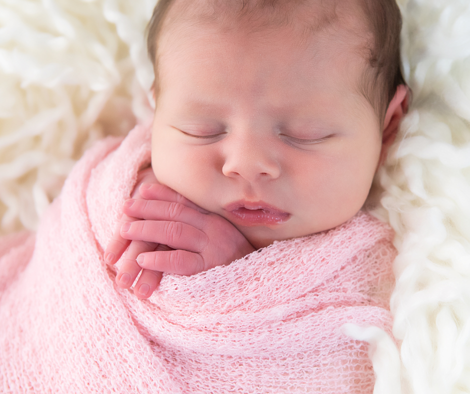 newborn  girl peacefully sleeping while swaddled